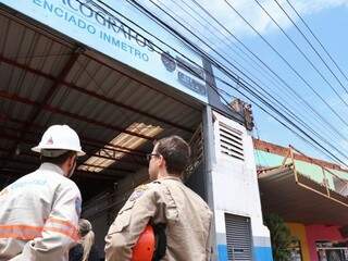 Empresário subiu no telhado de galpão e encostou na rede de alta tensão; bombeiro e técnico da Energisa trabalham no local (Foto: Henrique Kawaminami)