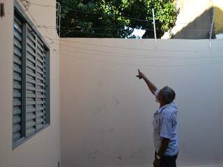 Idoso mostra as pegadas do bandido e a cerca elétrica estourada. (Foto: Viviane Oliveira)