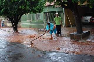 Após a chuva, José Luiz e Rosinha tiram pedras e lama da frente de casa. (Foto: Pedro Peralta)