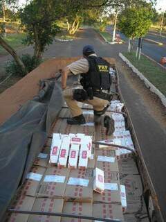 Policial chega carga de cigarros apreendida em Campo Grande. (Foto: Divulgação)