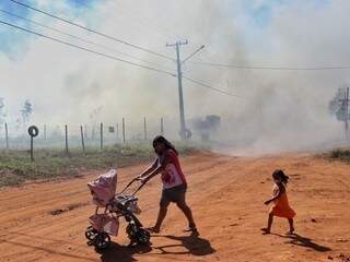 Famílias transitam em meio à fumaça. (Foto: Henrique Kawaminami)