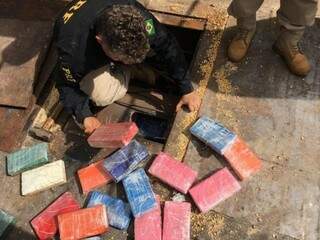Policiais retiram tabletes de cocaína de compartimento secreto em carreta de soja (Foto: Adilson Domingos)