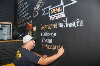 O empresário Wendell de Souza usa giz colorido para escrever na parede o menu flutuante do dia (Foto: Paulo Francis)