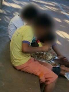 Crianças fazendo refeição na arquibancada da quadra (Foto: Direto das Ruas)
