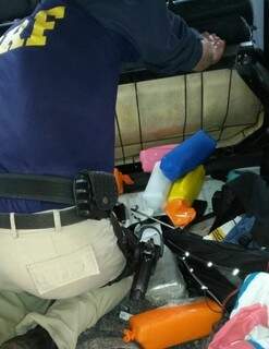 Policial retira pacotes de droga escondidos em tanque de combustível (Foto: Divulgação)