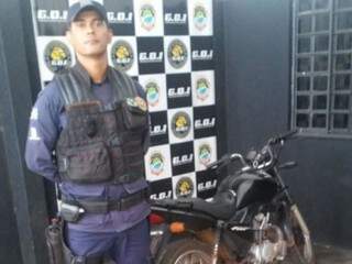 Policial Municipal ao lado da motocicleta encontrada no terreno. (Foto: Divulgação) 