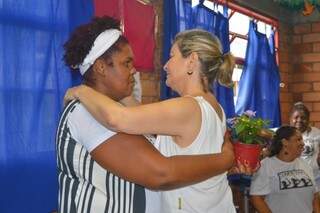 Odete Cardoso segurando a flor que recebeu e abraçando Maria Auxiliadora de Castro Borges (Foto: Alana Portela)