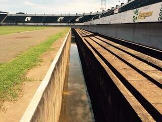 O fosso de piso e paredes de concreto cerca todo o gramado do Estádio Morenão. A água parada pode atrair o mosquito da dengue (Foto: Campo Grande News)