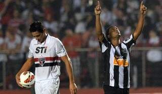 Enquanto Ronaldinho comemora gol em vitória, Ganso leva bola para saída de jogo do São Paulo (Nelson Almeida/AFP)