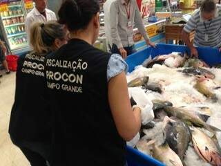Fiscais do órgão avaliando as condições de armazenamento dos peixas. (Foto: Divulgação) 