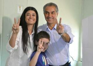Reinaldo Azambuja, a candidata a vice, Rose Modesto, e o neto do candidato, Leonardo, fazem o sinal da vitória no local de votação. (Foto: Marcelo Calazans)
