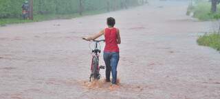 Para chegar em casa, diarista enfrenta rio empurrando a bicicleta. (Foto: João Garrigó)