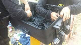Policiais desmontam mala onde foi encontrada cocaína em sacos de papel carbono (Foto: Divulgação/DOF)