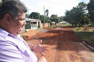 Presidente da Associação mostra um lado da rua com asfalto, outro sem. (Foto: Marcos Ermínio)