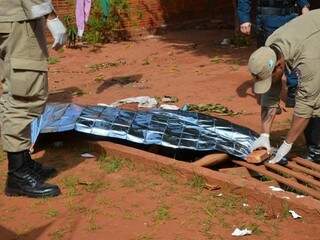 Militares do Corpo de Bombeiros cobrindo corpo de homem morto a facadas (Foto: Ivinotícias)
