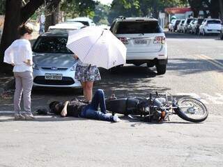 Enquanto socorro não vem, Milena faz sombra para a vítima com o guarda-sol. (Foto: Fernando Antunes) 