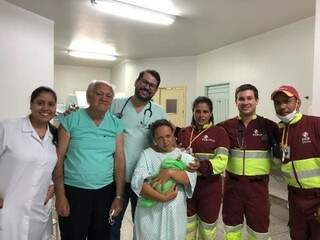 Mãe com bebê no colo e ao lado da equipe da CCR MSVia que realizou parto e de funcionários de hospital (Foto: Divulgação/CCR MSVia)