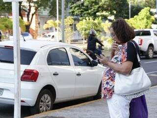 Mulher observa o celular enquanto passeia pelo Centro de Campo Grande (Foto: Kísie Ainoã)