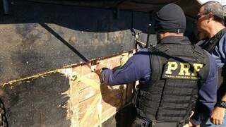 Policiais observam tabletes de maconha em fundo falso (Foto: Sidney Bronka/94 FM)