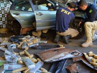 Policiais rodoviários federais retirando droga escondida em veículo (Foto: Divulgação/ PRF)