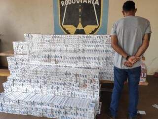 Suspeito preso ao lado dos 900 pacotes de cigarro que transportava. (Foto: Divulgação/PMR) 