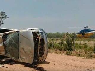 Camionete que capotou na estrada vicinal e ao fundo helicóptero usado no resgate as vítimas. (Foto: Divulgação/PRF) 