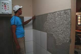 Bruno mostra parte dos azulejos que caiu na sua casa.