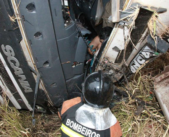  Carreta tomba ao passar por buracos e motorista fica preso nas ferragens