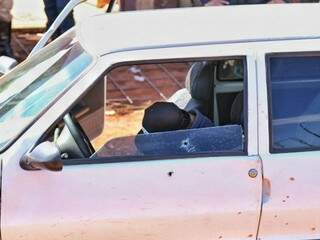 Uno com a porta aberta, perfurações causadas por tiros e uma das vítimas morta, no banco do motorista (Foto: Fernando Antunes)