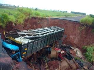 Caminhão boiadeiro caído em buraco aberto pela chuva na MS-475 (Foto: Nova News)