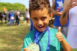 Filho de Eliane mostra a medalha que receceu por participar de corrida Kid. (Foto: André Bittar)