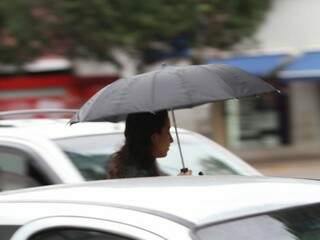 Mulher andando com guarda-chuva e casaco, na manhã de hoje, pelas ruas do Centro de Campo Grande (Foto: Saul Schramm)
