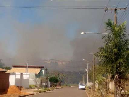 Incêndio toma conta de matagal e vento joga fumaça contra residências
