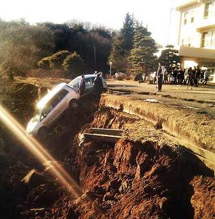 Carro pendurado em cratera aberta por terremoto. (Foto: AFP)