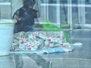 Mulher dormindo dentro de agência bancária no Centro de Campo Grande. (Foto: André Bittar)