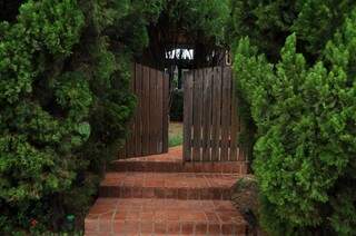 Portãozinho de madeira contrasta com a fachada coberta por arbustos. (Foto: Marcelo Calazans)