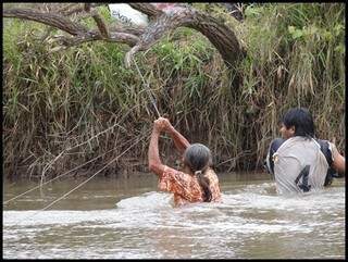 Após ataque, travessia de rio foi feita segurando em fio de arame. (Foto: Divulgação/MPF)