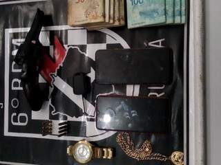 Arma, jóias e dinheiro apreendido no caso. (Foto: Diário Corumbaense) 