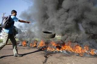 Manifestante joga pneu para ser queimado na Avenida Guairucus. (Foto: Marcelo Victor)