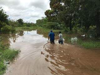 Moradores de Bela Vista caminham sobre região alagada após temporal (Foto: Edinho Corrêa / Diário da Fronteira)