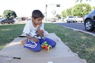 O menino cubano brinca no canteiro enquanto o pai pede ajuda na principal avenida da cidade. 