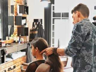 O cabeleireiro Haysteen Luckas Alves Carneiro amarrando o cabelo de Maria Eduarda de Andrade Queiroz para o corte (Foto: Henrique Kawmaninami)