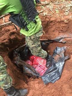 Agente da Narcóticos do Paraguai em buraco onde estavam escondidos os fardos de maconha (Foto: Porã News)
