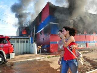 Funcionárias deixam loja incendiada na avenida Costa e Silva, que provocou tumulto no trânsito e interditou terminal de ônibus. (Foto: Luciano Muta)