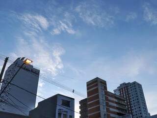 Imagem mostra dia amanhecendo com céu entre nuvens na Rua 14 de Julho, no Centro de Campo Grande (Foto: Henrique Kawaminami) 