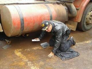 Policial do DOF retira tabletes de cocaína de tanque de carreta apreendida hoje entre Amambai e Ponta Porã (Foto: Divulgação/DOF)