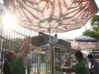 Vento pós-chuva quase leva guarda-sol de Rosângela, que vende pipoca na Praça Ary Coelho; depois do rápido temporal, sol iluminou céu da Capital (Foto: Marcos Ermínio)