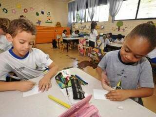 Duas crianças fazendo atividades com lápis de cor, em sala de aula (Foto: Agência Brasil/Arquivo)