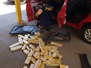 Policial retirando a droga que estava sob a lataria do carro. (Foto: Divulgação) 