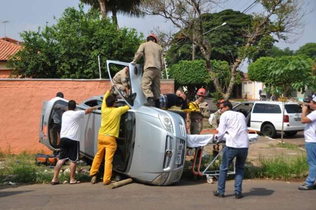 Ap&oacute;s ser atingido por t&aacute;xi, carro tomba e motorista fica preso nas ferragens